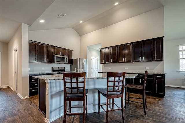 18623 Swainboro Dr, New Caney, TX 77357 - kitchen with appliances with stainless steel finishes, dark wood-type flooring, an island with sink, dark brown cabinets, and a kitchen breakfast bar