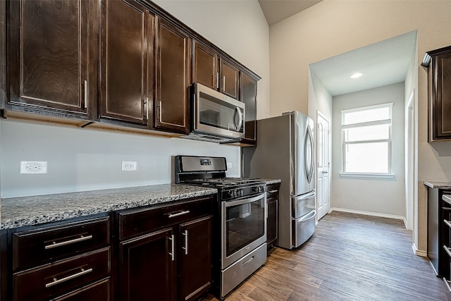 18623 Swainboro Dr, New Caney, TX 77357 - kitchen featuring stainless steel appliances, dark brown cabinets, wood finished floors, and stone counters