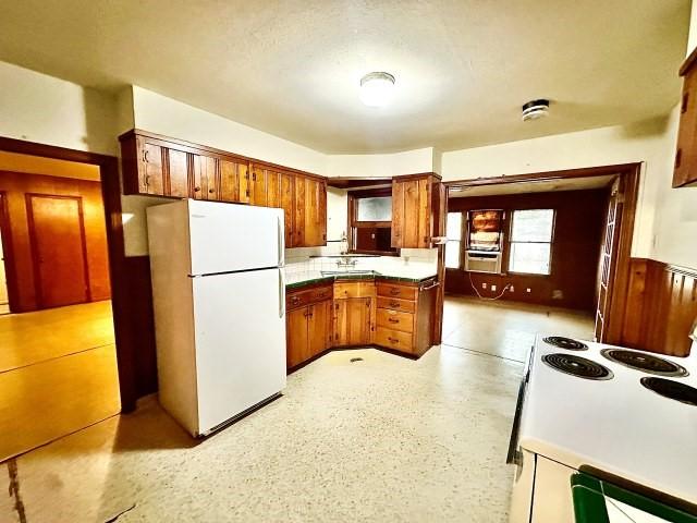 515 Vaky St, Corpus Christi, TX 78404 - kitchen with white appliances, brown cabinetry, cooling unit, tasteful backsplash, and a peninsula