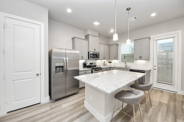 9016 Lonestar River Ln, Houston, TX 77080 - kitchen featuring stainless steel appliances, gray cabinetry, a center island, a breakfast bar area, and light wood-style floors