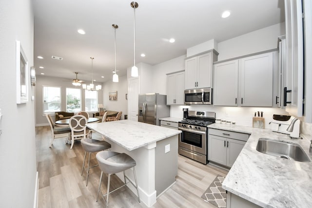 9016 Lonestar River Ln, Houston, TX 77080 - kitchen featuring appliances with stainless steel finishes, a kitchen bar, light wood finished floors, a center island, and gray cabinetry