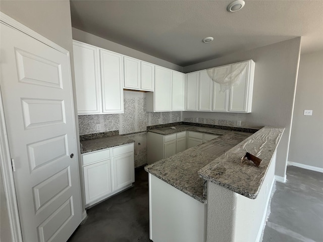 2532 Hawks Eye Dr, Conroe, TX 77301 - kitchen featuring concrete flooring, a peninsula, stone countertops, and white cabinetry
