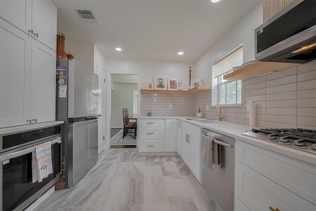 7634 Braesdale Ln, Houston, TX 77071 - kitchen featuring appliances with stainless steel finishes, open shelves, white cabinetry, tasteful backsplash, and light countertops