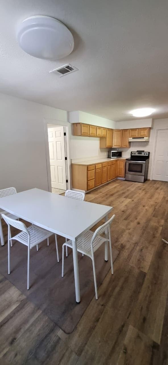 10626 Fussel Rd, Conroe, TX 77385 - kitchen with appliances with stainless steel finishes, wood finished floors, under cabinet range hood, and light countertops