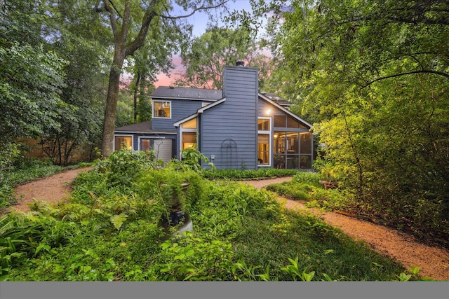 11 Leaf Trace Ct, Spring, TX 77381 - back of house at dusk featuring a sunroom and a chimney