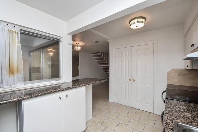 2635 Marilee Ln Unit 2635, Houston, TX 77057 - kitchen with white cabinets, light tile patterned flooring, dark stone countertops, and under cabinet range hood