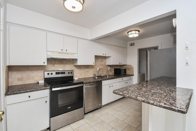 2635 Marilee Ln Unit 2635, Houston, TX 77057 - kitchen with stainless steel appliances, under cabinet range hood, backsplash, white cabinetry, and light tile patterned flooring
