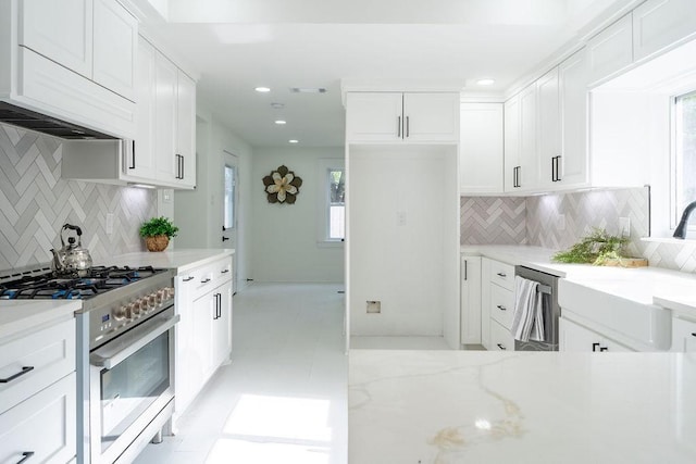 1020 E 16th St, Houston, TX 77009 - kitchen featuring appliances with stainless steel finishes, backsplash, light stone counters, white cabinets, and recessed lighting
