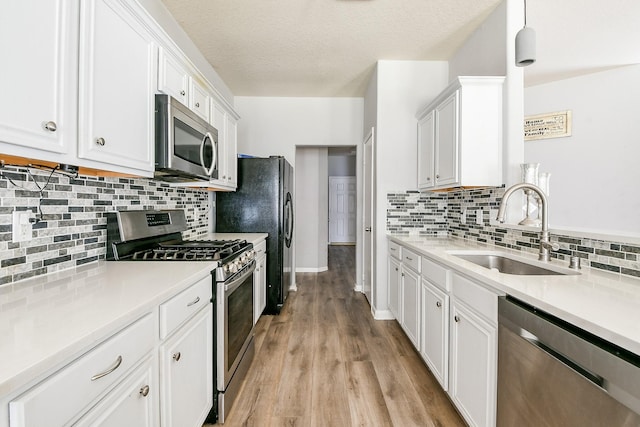 2526 Hidden Park Ln, Conroe, TX 77385 - kitchen with stainless steel appliances, white cabinetry, tasteful backsplash, light countertops, and light wood-style flooring