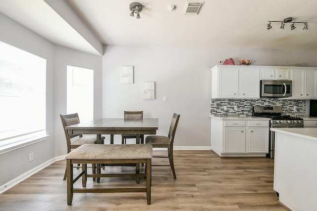 2526 Hidden Park Ln, Conroe, TX 77385 - dining space with light wood-style floors and rail lighting