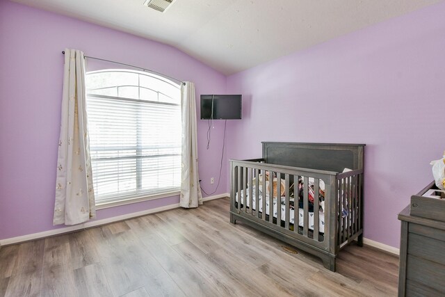 2526 Hidden Park Ln, Conroe, TX 77385 - bedroom featuring lofted ceiling, wood finished floors, and a nursery area