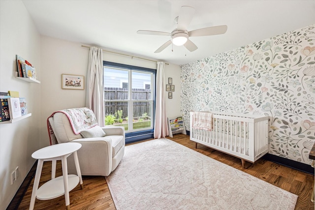 1247 Martin St, Houston, TX 77018 - bedroom featuring a nursery area, wallpapered walls, wood finished floors, and a ceiling fan