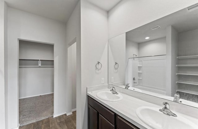 23322 Pelham Prairie Ln, Spring, TX 77373 - bathroom featuring wood finished floors, double vanity, a walk in closet, and shower / bath combination