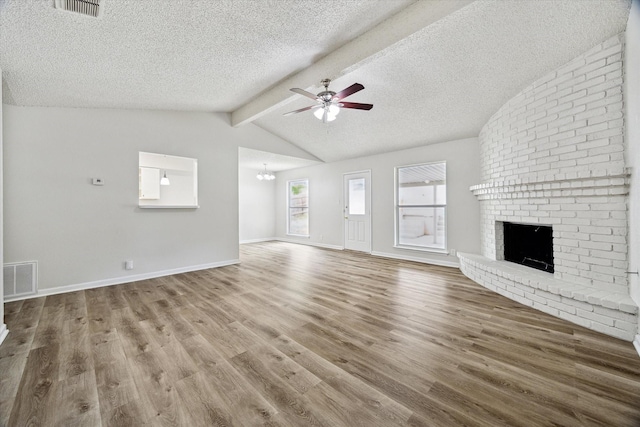 11331 Woollcott St, San Antonio, TX 78251 - unfurnished living room with ceiling fan, a brick fireplace, a textured ceiling, wood finished floors, and a chandelier