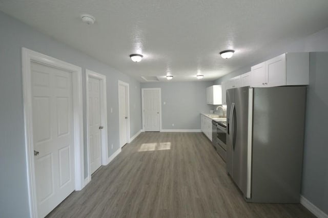 3007 Tuam St, Houston, TX 77004 - kitchen featuring freestanding refrigerator, white cabinetry, wood finished floors, light countertops, and stove