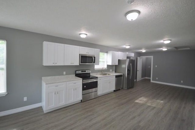 3007 Tuam St, Houston, TX 77004 - kitchen with appliances with stainless steel finishes, wood finished floors, white cabinets, light countertops, and a textured ceiling