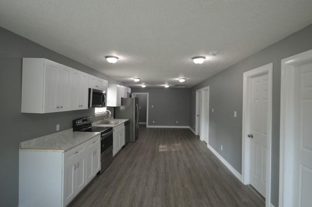 3007 Tuam St, Houston, TX 77004 - kitchen featuring appliances with stainless steel finishes, white cabinetry, light countertops, dark wood-style floors, and a textured ceiling