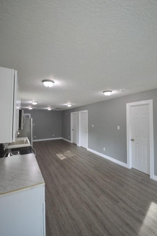 3007 Tuam St, Houston, TX 77004 - kitchen with dark wood-style flooring, white cabinetry, a textured ceiling, open floor plan, and light countertops