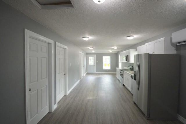 3007 Tuam St, Houston, TX 77004 - kitchen with stainless steel appliances, white cabinetry, a textured ceiling, and wood finished floors