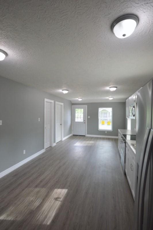 3007 Tuam St, Houston, TX 77004 - kitchen with stainless steel appliances, a textured ceiling, dark wood-style floors, open floor plan, and white cabinetry