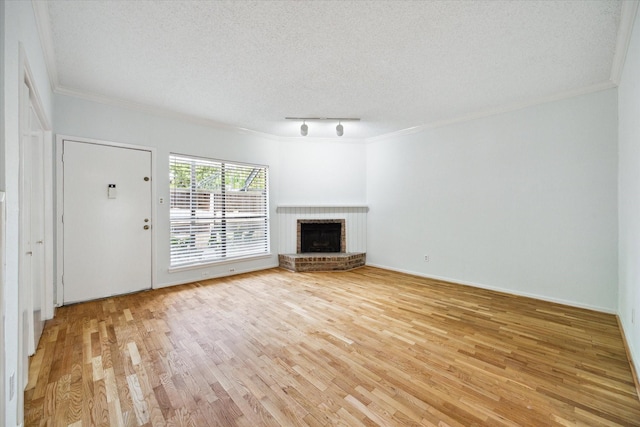 1100 Augusta Dr Unit 63, Houston, TX 77057 - unfurnished living room featuring crown molding, light wood-style flooring, track lighting, a fireplace, and a textured ceiling