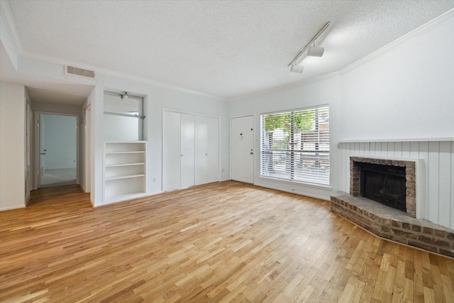 1100 Augusta Dr Unit 63, Houston, TX 77057 - unfurnished living room with ornamental molding, a textured ceiling, light wood-type flooring, built in shelves, and a brick fireplace