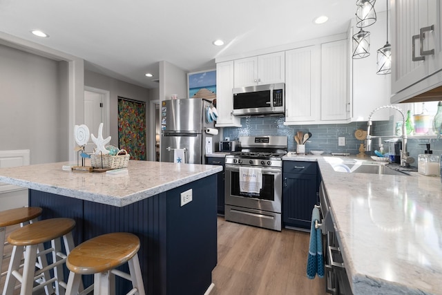 16711 Kingston Way, Galveston, TX 77554 - kitchen with appliances with stainless steel finishes, a breakfast bar area, backsplash, a center island, and light stone countertops