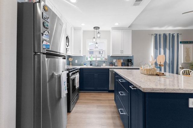 16711 Kingston Way, Galveston, TX 77554 - kitchen featuring appliances with stainless steel finishes, blue cabinets, decorative backsplash, white cabinetry, and hanging light fixtures