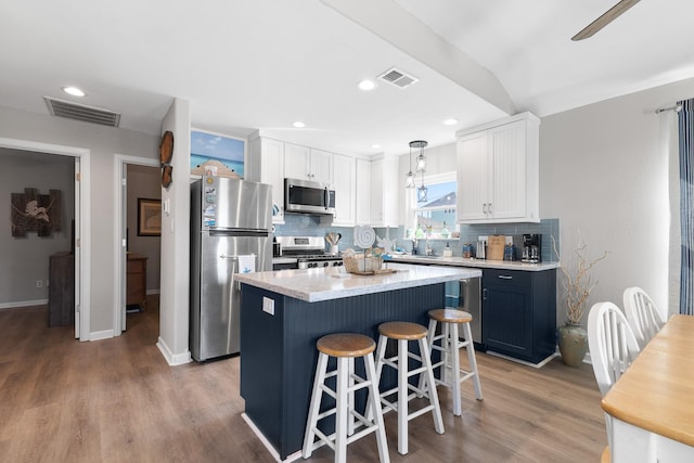 16711 Kingston Way, Galveston, TX 77554 - kitchen featuring stainless steel appliances, backsplash, white cabinetry, light wood-type flooring, and light countertops