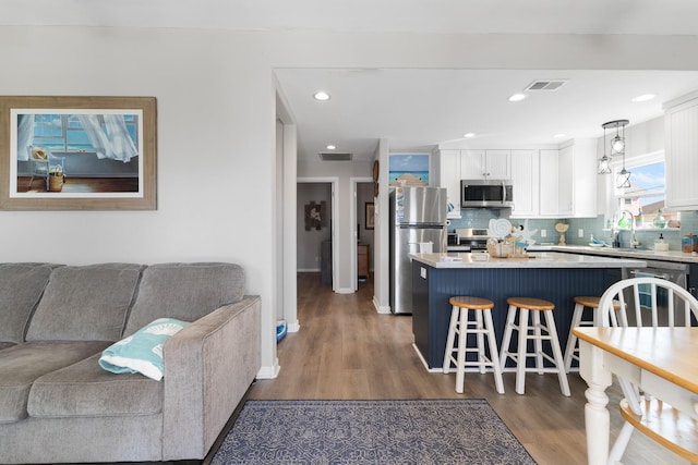 16711 Kingston Way, Galveston, TX 77554 - kitchen with dark wood-style flooring, stainless steel appliances, white cabinetry, open floor plan, and a kitchen bar