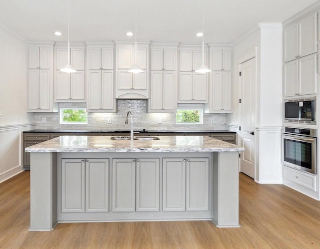 306 Felt Cir, Houston, TX 77011 - kitchen featuring stainless steel oven, light wood-type flooring, black microwave, backsplash, and recessed lighting