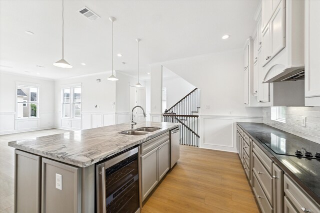 306 Felt Cir, Houston, TX 77011 - kitchen featuring wine cooler, a decorative wall, dishwasher, a kitchen island with sink, and stone counters