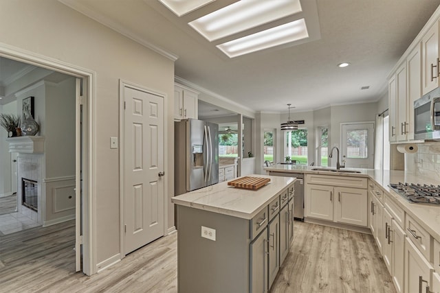 22811 Northampton Pines Dr, Spring, TX 77389 - kitchen featuring stainless steel appliances, light wood-style floors, a kitchen island, crown molding, and a tiled fireplace