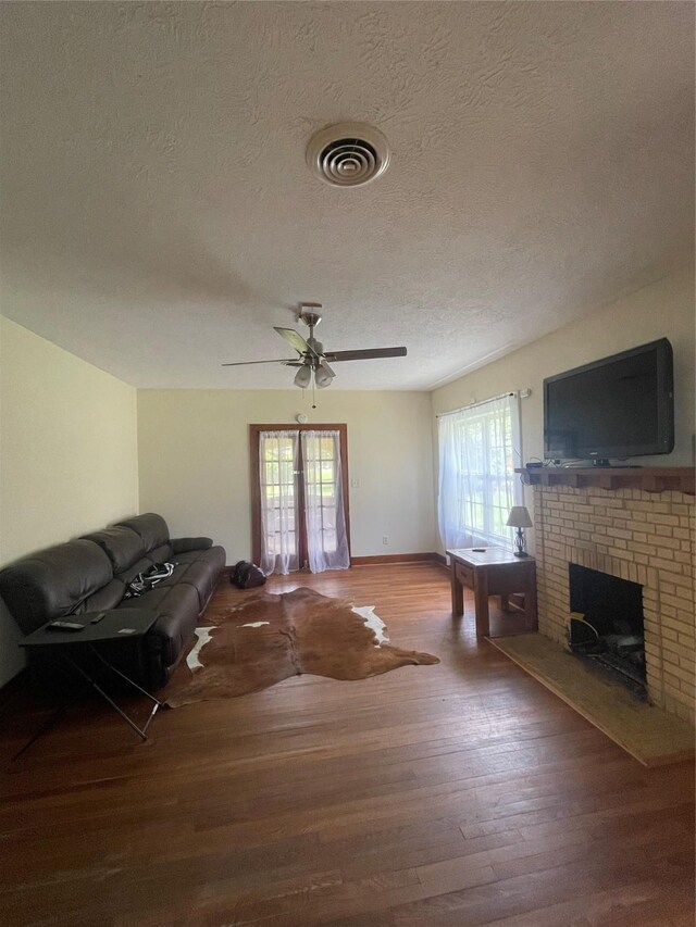 926 S Cass St, Centerville, TX 75833 - living room featuring a textured ceiling, wood finished floors, a fireplace, and ceiling fan