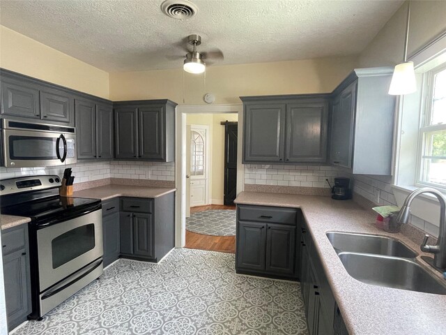 926 S Cass St, Centerville, TX 75833 - kitchen with stainless steel appliances, a textured ceiling, decorative backsplash, light countertops, and a ceiling fan