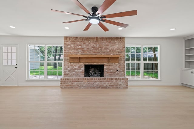 8215 Twining Oaks Ln, Spring, TX 77379 - unfurnished living room featuring plenty of natural light, recessed lighting, a brick fireplace, ceiling fan, and wood finished floors