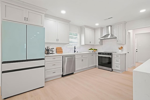 8215 Twining Oaks Ln, Spring, TX 77379 - kitchen with wall chimney exhaust hood, appliances with stainless steel finishes, light wood-type flooring, tasteful backsplash, and recessed lighting