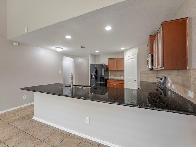 419 Eastern Phoebe, San Antonio, TX 78253 - kitchen with appliances with stainless steel finishes, brown cabinets, arched walkways, decorative backsplash, and a peninsula