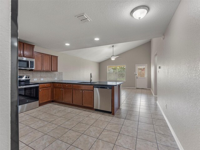 419 Eastern Phoebe, San Antonio, TX 78253 - kitchen with appliances with stainless steel finishes, a textured wall, decorative backsplash, a peninsula, and vaulted ceiling