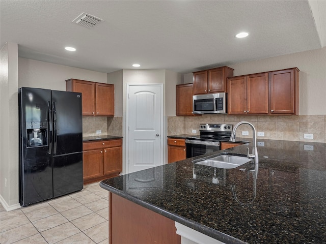 419 Eastern Phoebe, San Antonio, TX 78253 - kitchen with stainless steel appliances, brown cabinetry, dark stone counters, backsplash, and a peninsula
