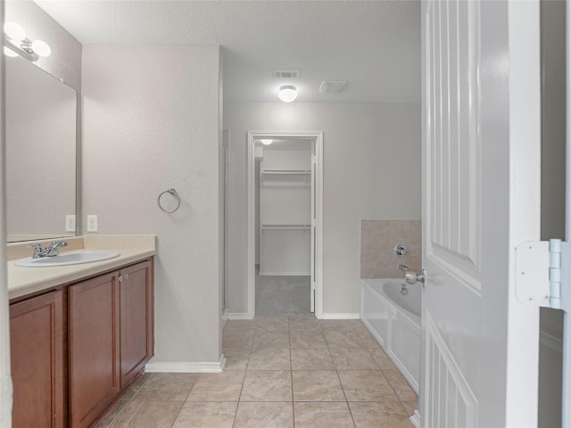 419 Eastern Phoebe, San Antonio, TX 78253 - bathroom with a bath, vanity, a walk in closet, a textured ceiling, and tile patterned floors