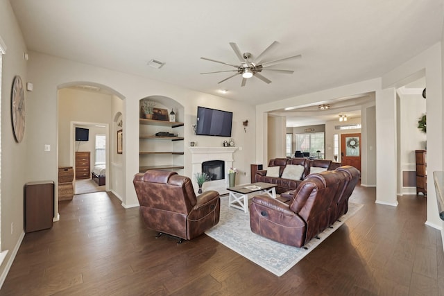 18114 Rustic Springs Dr, Tomball, TX 77375 - living area featuring ceiling fan, a glass covered fireplace, dark wood-style floors, and built in shelves