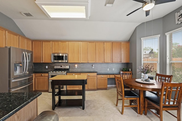 18114 Rustic Springs Dr, Tomball, TX 77375 - kitchen featuring stainless steel appliances, lofted ceiling, decorative backsplash, a ceiling fan, and dark stone countertops