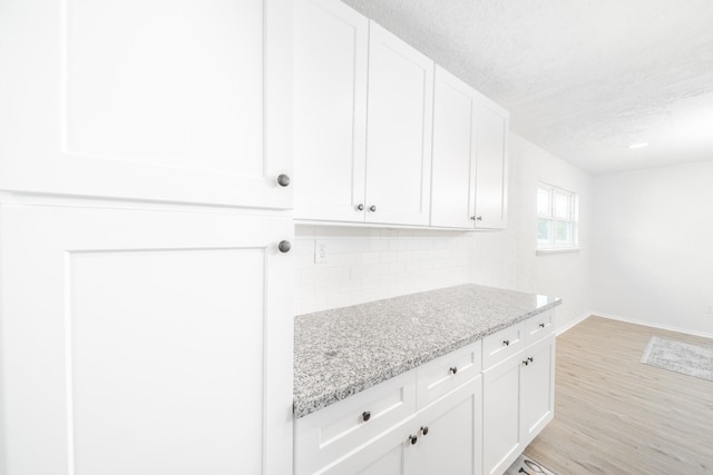8318 Hanfro Ln, Houston, TX 77088 - kitchen with a textured ceiling, white cabinetry, light stone countertops, and backsplash
