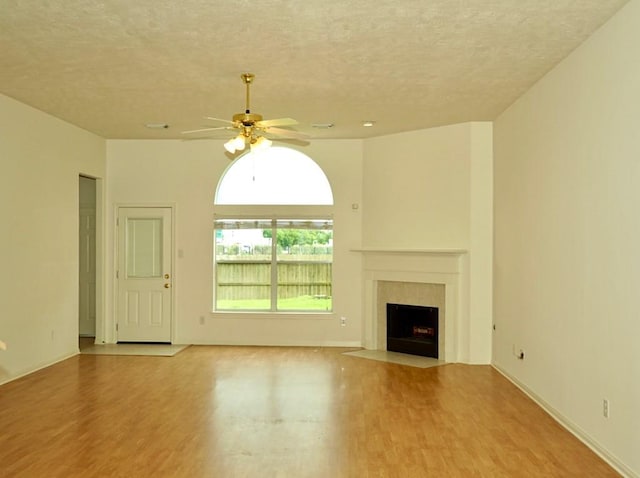 14811 Horse Creek Ln, Sugar Land, TX 77498 - unfurnished living room with wood finished floors, a textured ceiling, ceiling fan, and a fireplace with flush hearth