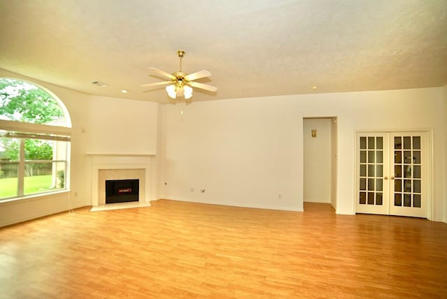 14811 Horse Creek Ln, Sugar Land, TX 77498 - unfurnished living room with light wood-style floors, a ceiling fan, a fireplace with flush hearth, and french doors