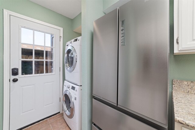 2601 S Braeswood Blvd Unit 302, Houston, TX 77025 - laundry room with cabinet space, stacked washing machine and dryer, and light tile patterned floors
