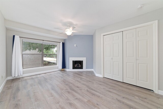 2601 S Braeswood Blvd Unit 302, Houston, TX 77025 - unfurnished living room featuring a ceiling fan, light wood finished floors, and a tiled fireplace