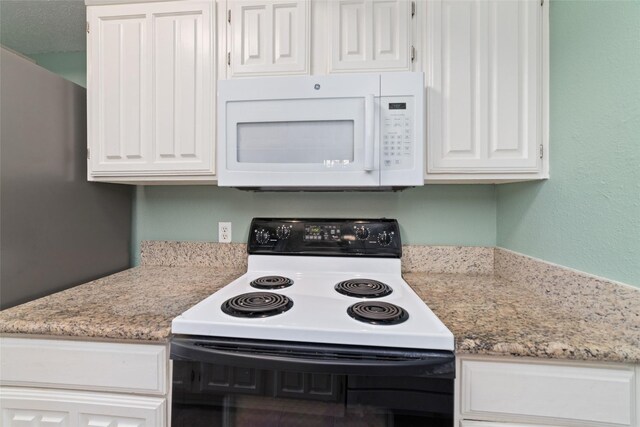 2601 S Braeswood Blvd Unit 302, Houston, TX 77025 - kitchen featuring range with electric stovetop, white microwave, white cabinetry, and light stone countertops