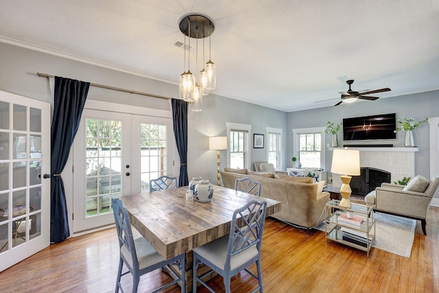 936 W Temple St, Houston, TX 77009 - dining area featuring french doors, light wood-style floors, a brick fireplace, ceiling fan, and crown molding